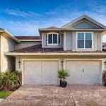 Freshly painted two-story Charleston SC home with cream siding, double garage, and tropical landscaping